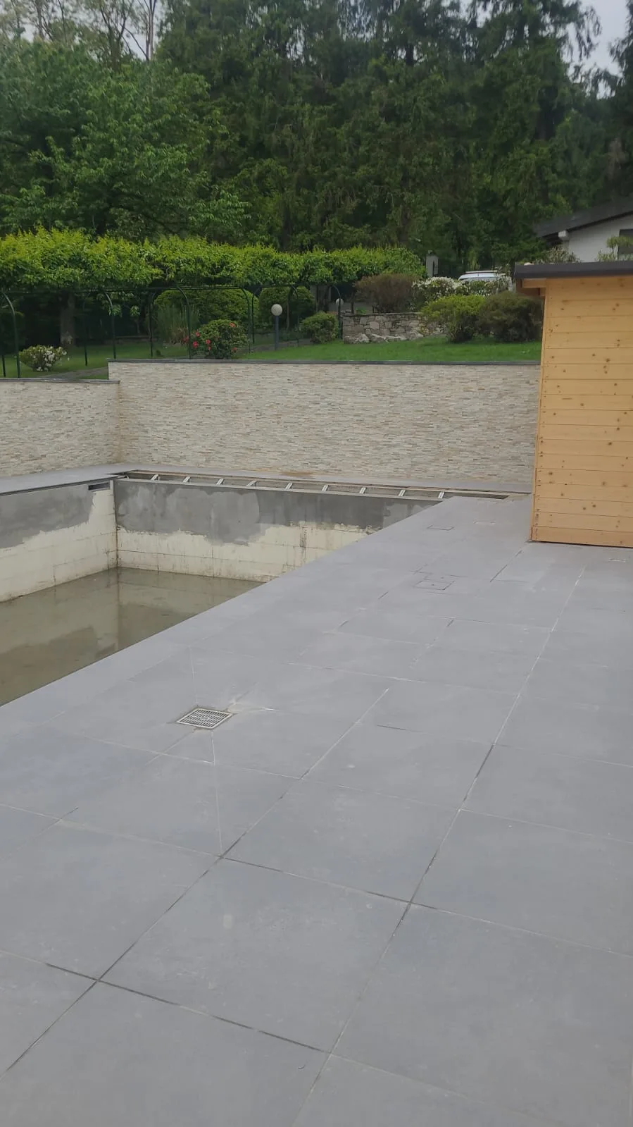 Pavimentazione in gres del bordo piscina completata, vasca ancora vuota